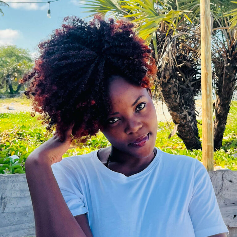Peace Kasinja - Co-Founder and Social Media Manager for East Africa Travel from the Port of Peace - sits on a wooden bench at the beach