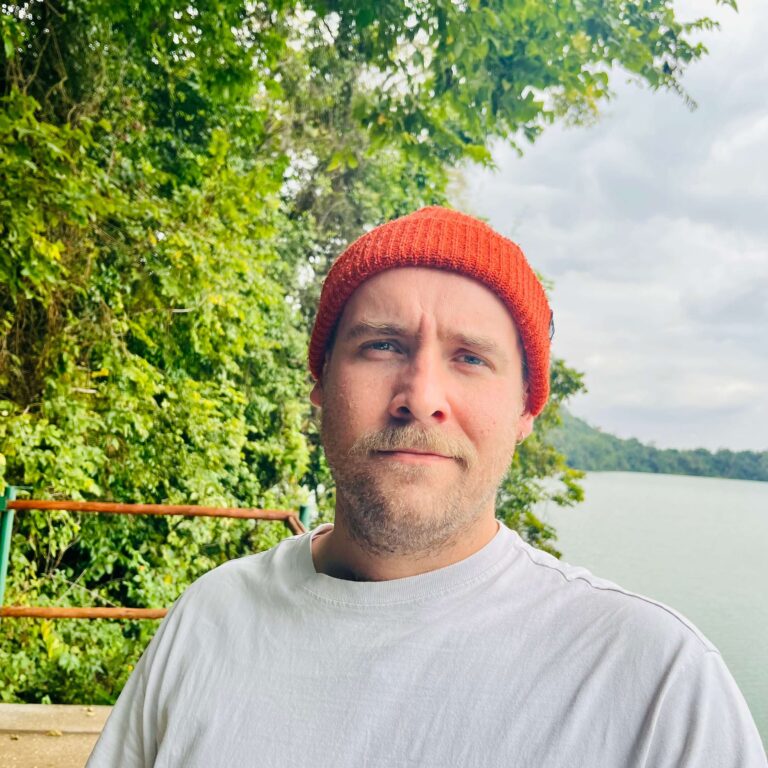 Tom Rusbridge - Co-Founder and Website Manager - stood on a dock by a lake